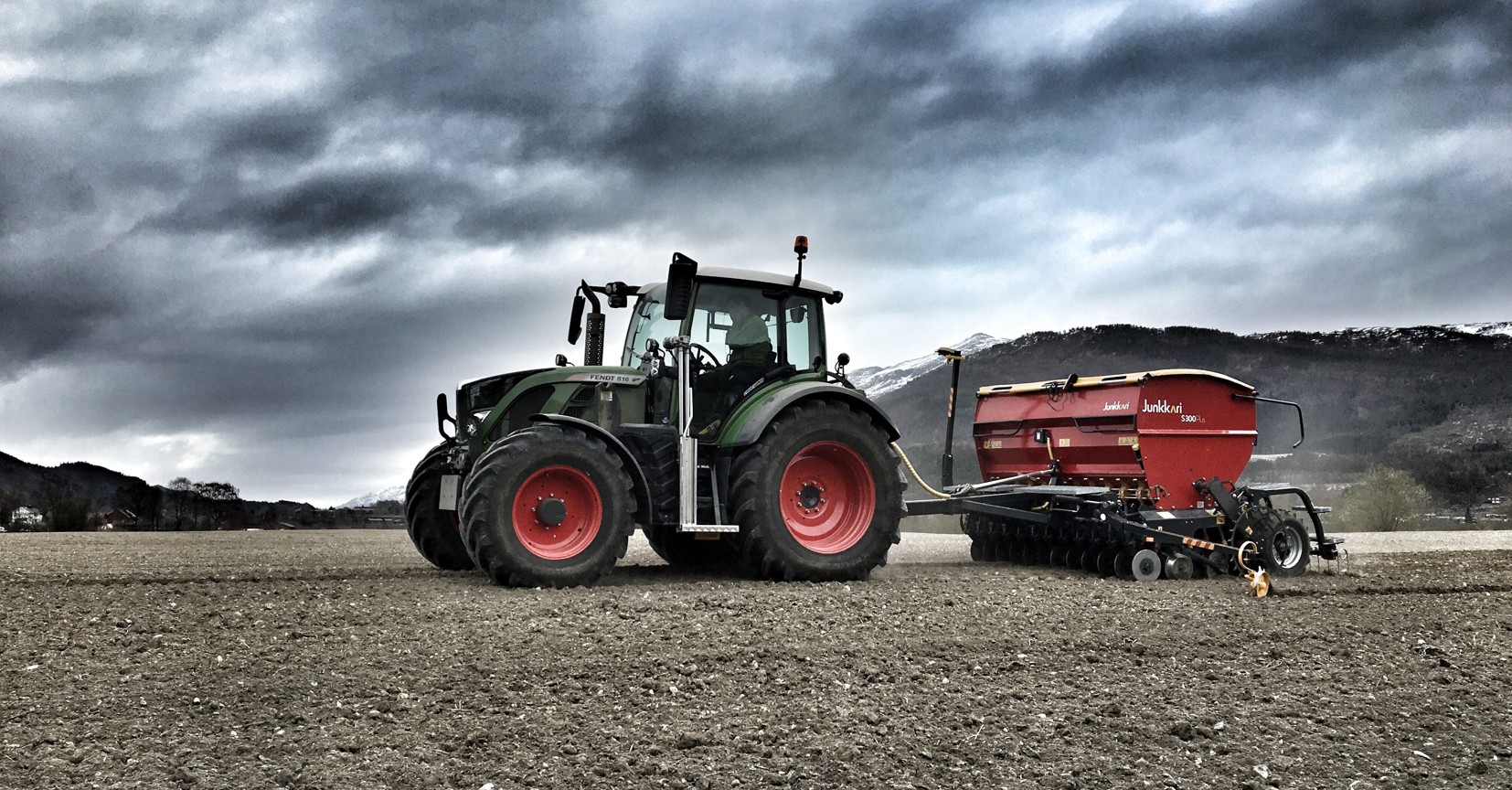 Fendt tractor working the fields under dramatic stormy sky